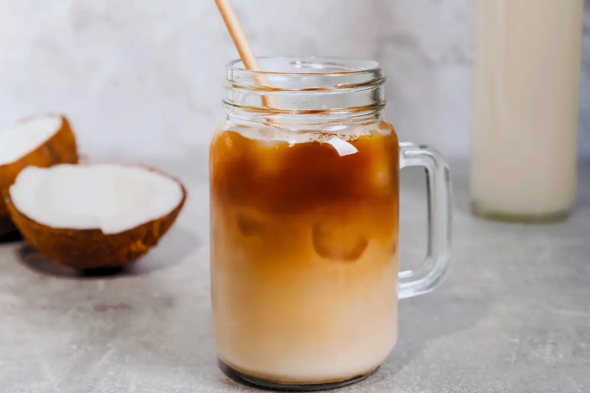 a glass jar with a straw in it and a coconut