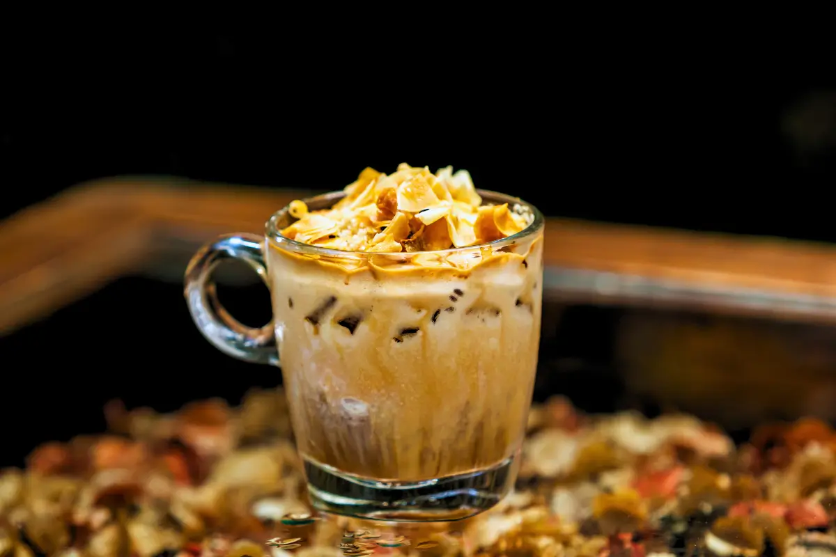 a glass cup of coffee with brown liquid and brown food