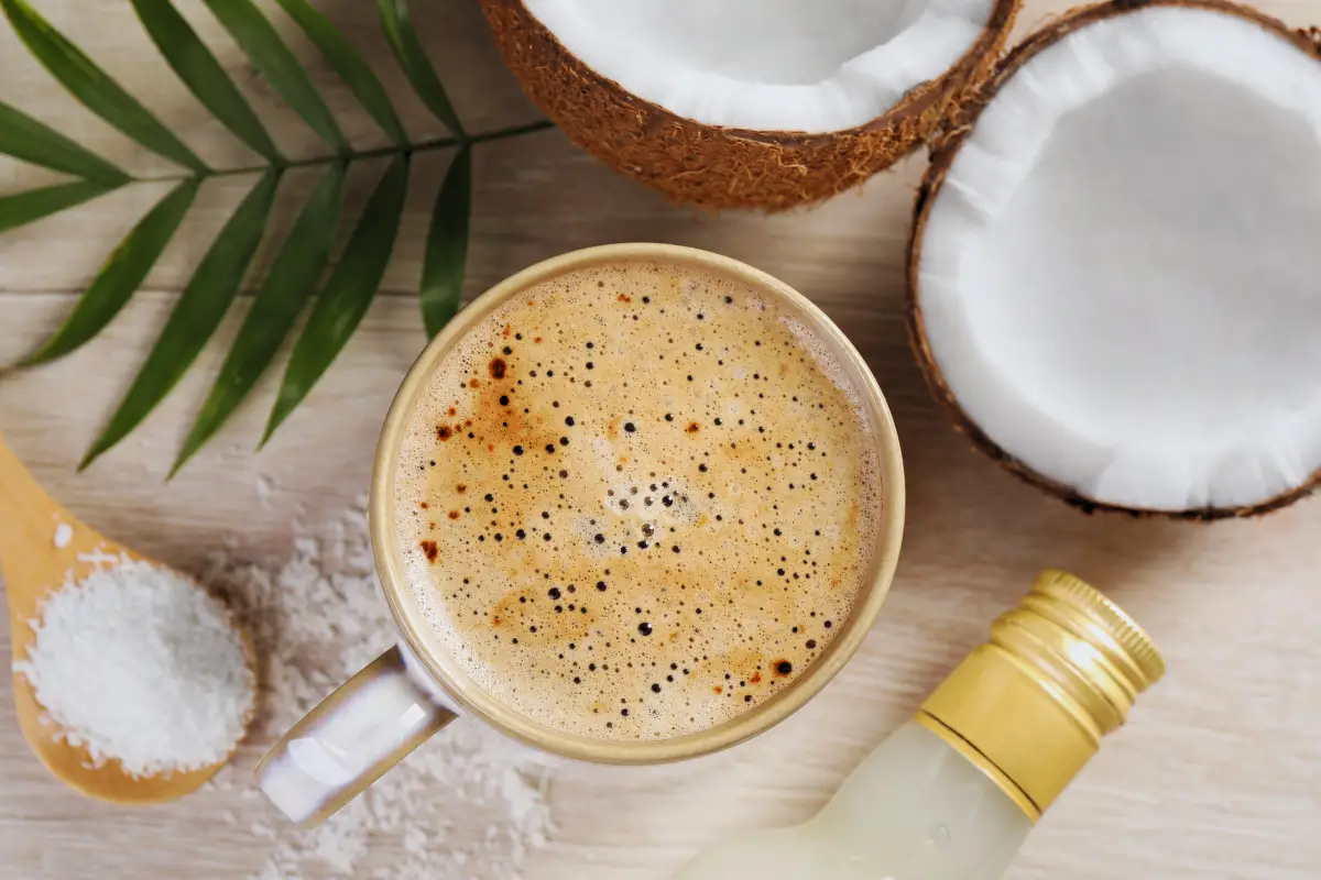 a cup of coffee next to coconuts and a bottle of liquid